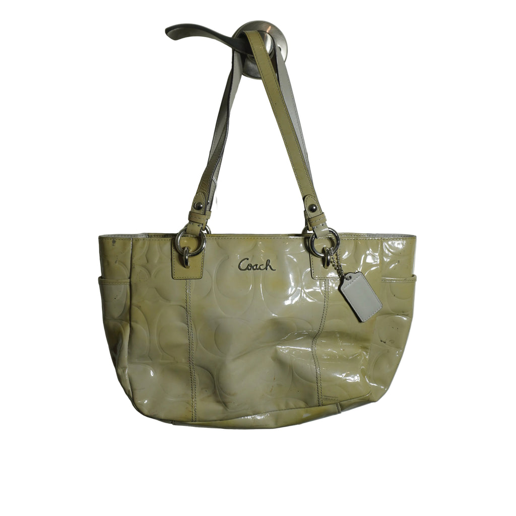 Beige handbag with 'Coach' logo on a white door